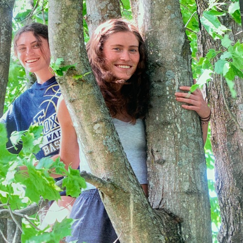 Teen girls stand next to trees